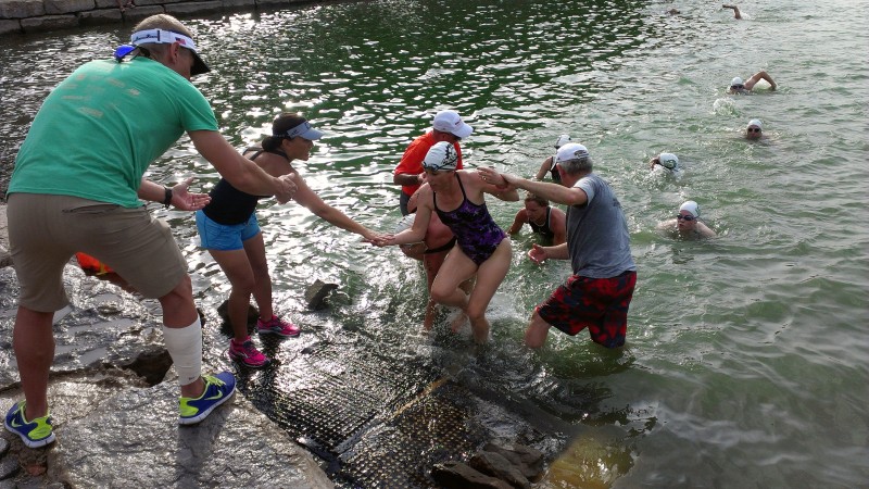 Club members Jess Z. (black tank top), Paul S. (Orange shirt), and Mike W. (Grey Shirt) help New Town swimmers exit the water